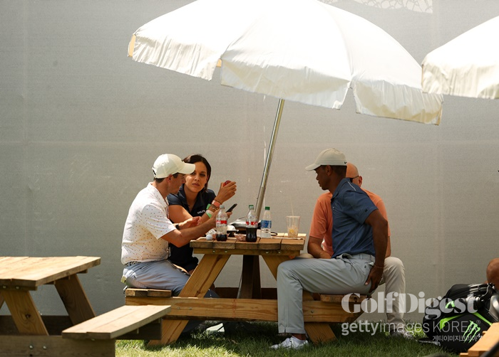 로리 매킬로이와 타이거 우즈가 대회장에 마련된 테이블에 앉아 이야기를 나누고 있다.